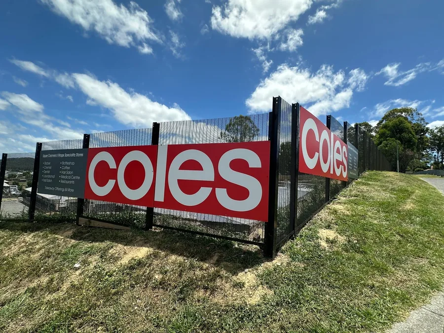 Coles branded panels and a specialty store board fixed along black security fencing